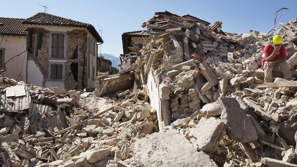 Mann sitzt auf Trümmern eingestürzter Häuser in Amatrice | Bildquelle: dpa