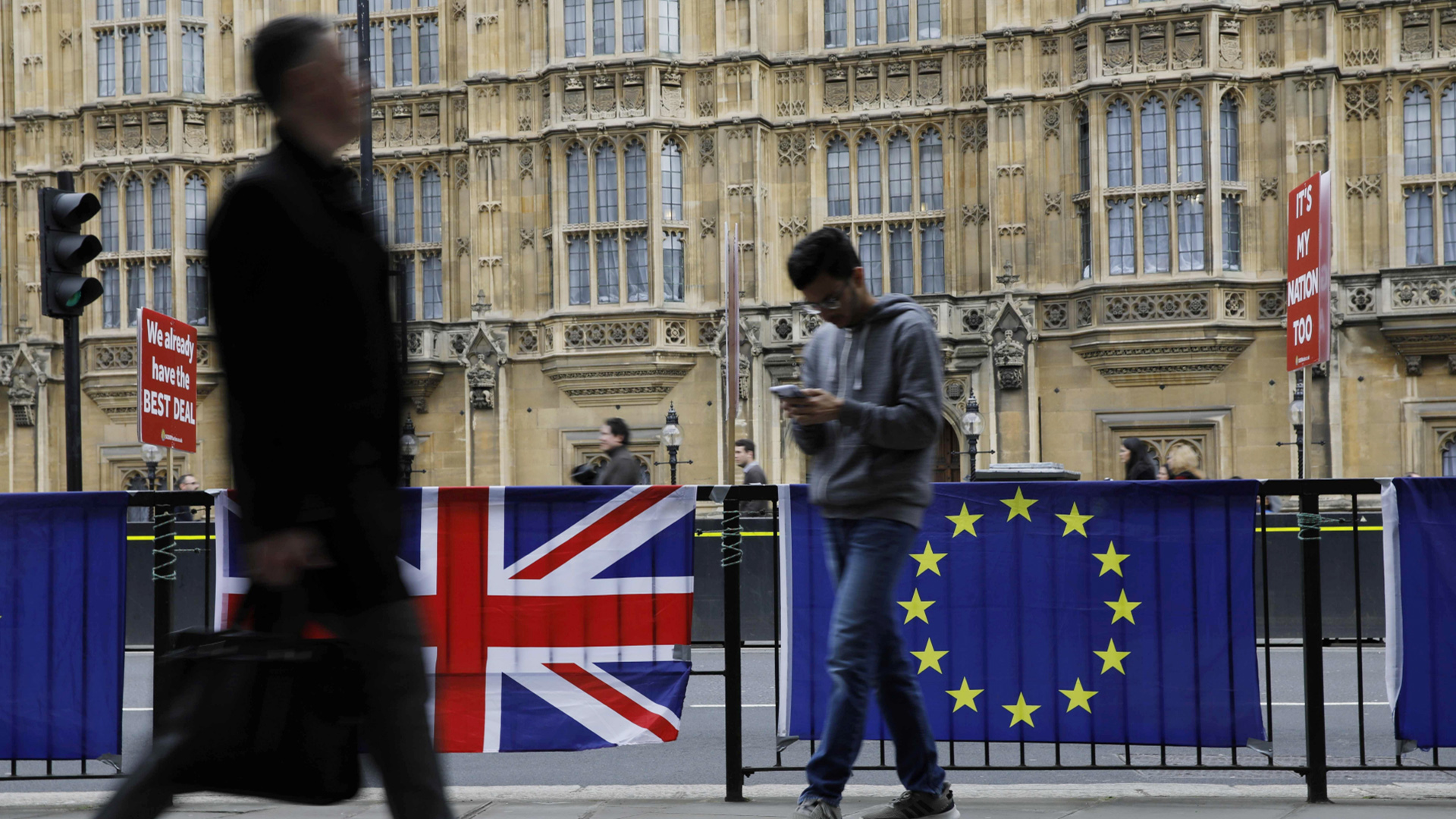 Passanten laufen an der britischen und europäischen Flagge vor dem britischen Parlament vorbei. | Bildquelle: AFP