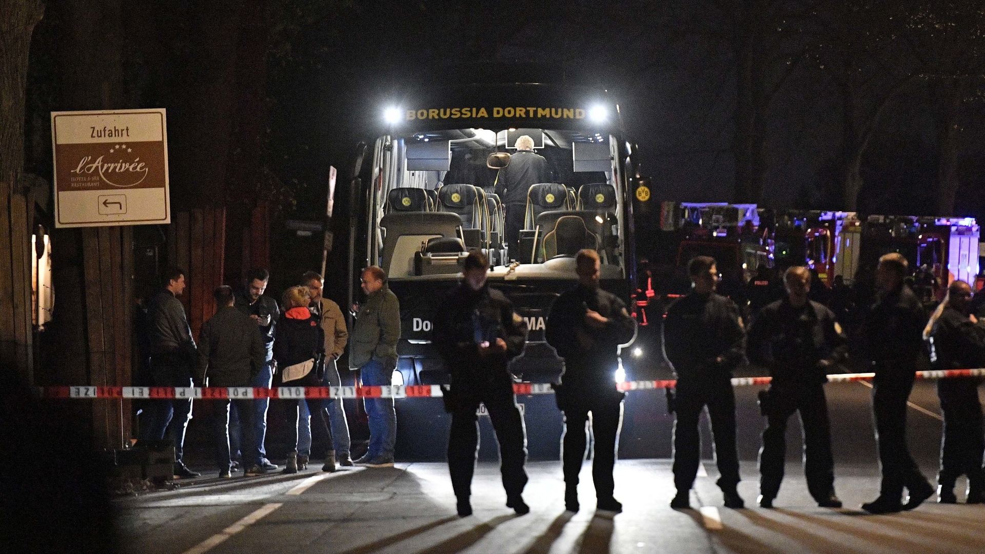 Polizisten stehen vor dem beschädigten BVB-Mannschaftsbus. | Bildquelle: AP