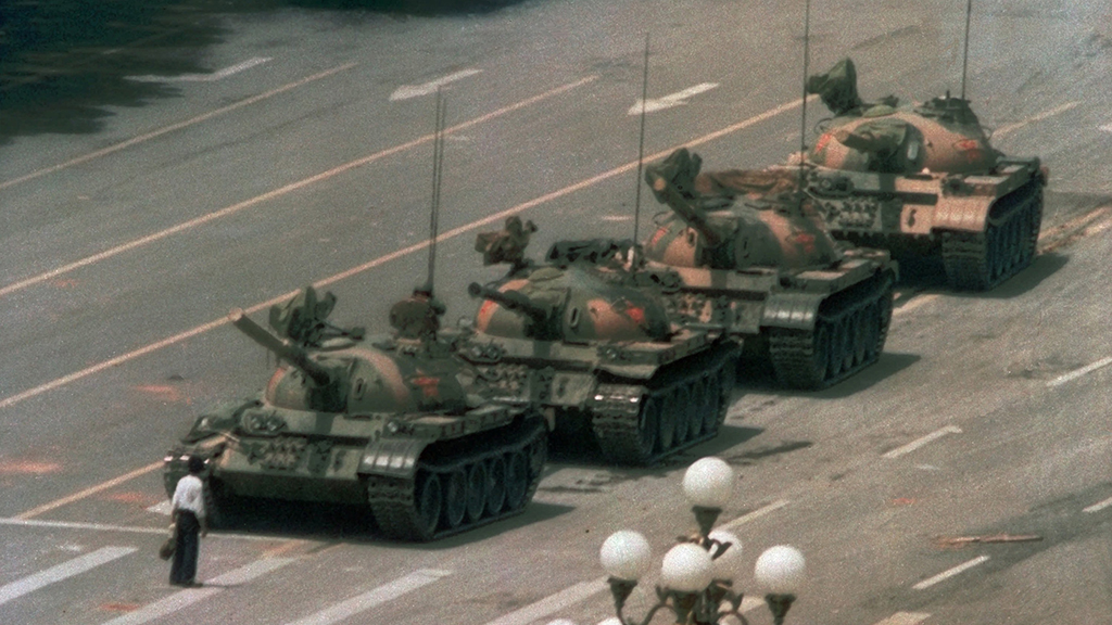 Ein Mann steht vor einem Panzer-Konvoi