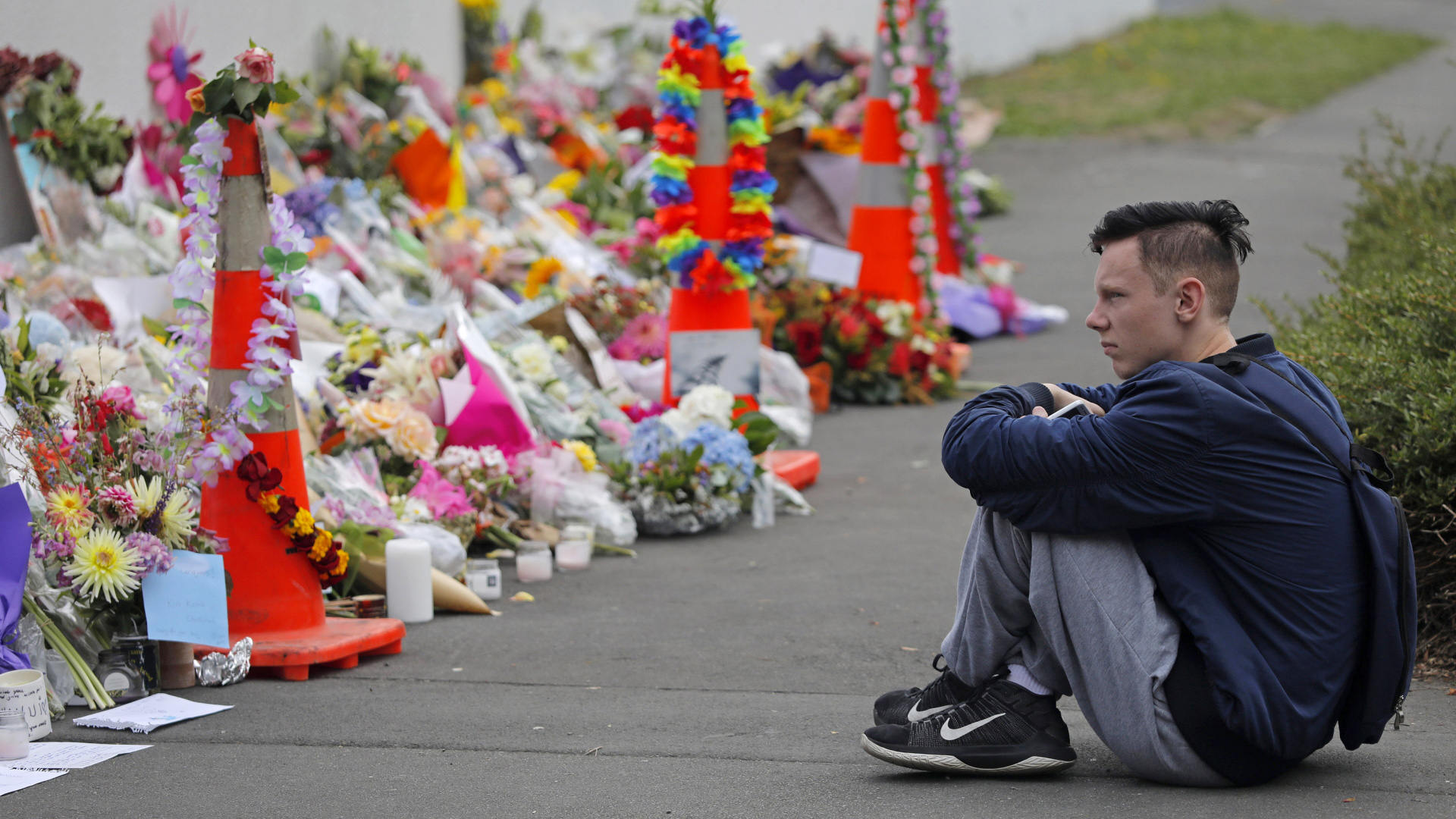 Ein Schüler sitzt vor einer Blumenwand in einem Park nahe der Al-Noor-Moschee in Christchurch | Bildquelle: AP