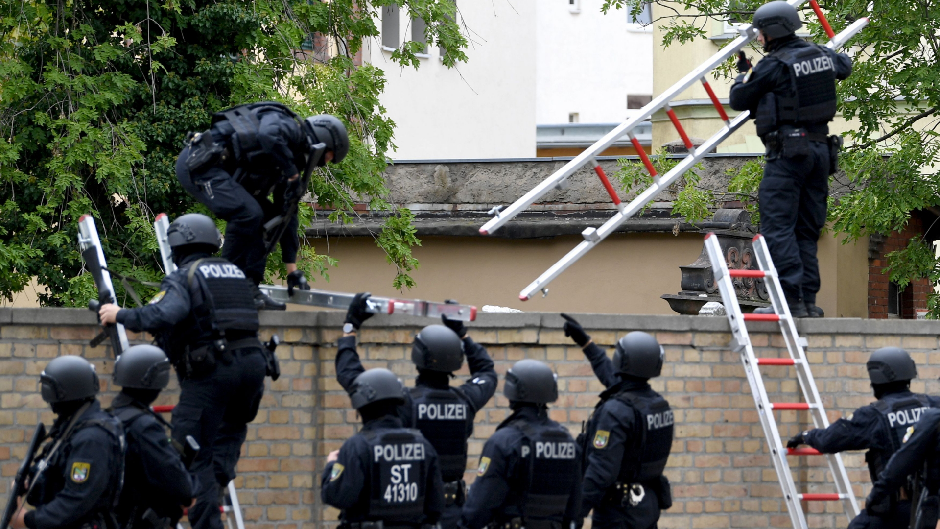 Polizeikräfte steigen über die Friedhofsmauer auf der Gelände der Synagoge in Halle. | Bildquelle: FILIP SINGER/EPA-EFE/REX