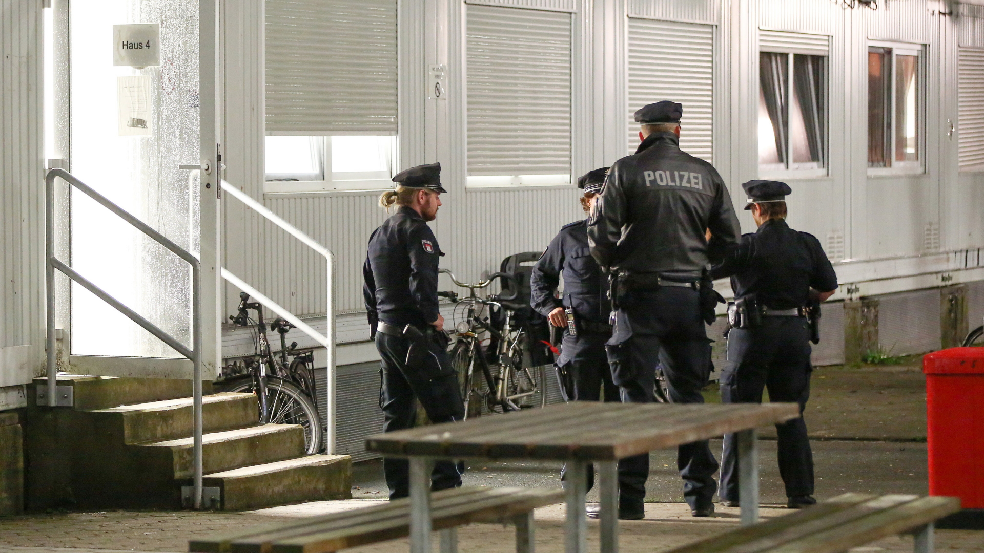Polizisten stehen vor einem der Wohncontainer der Flüchtlingsunterkunft in Hamburg-Langenhorn. | Bildquelle: dpa