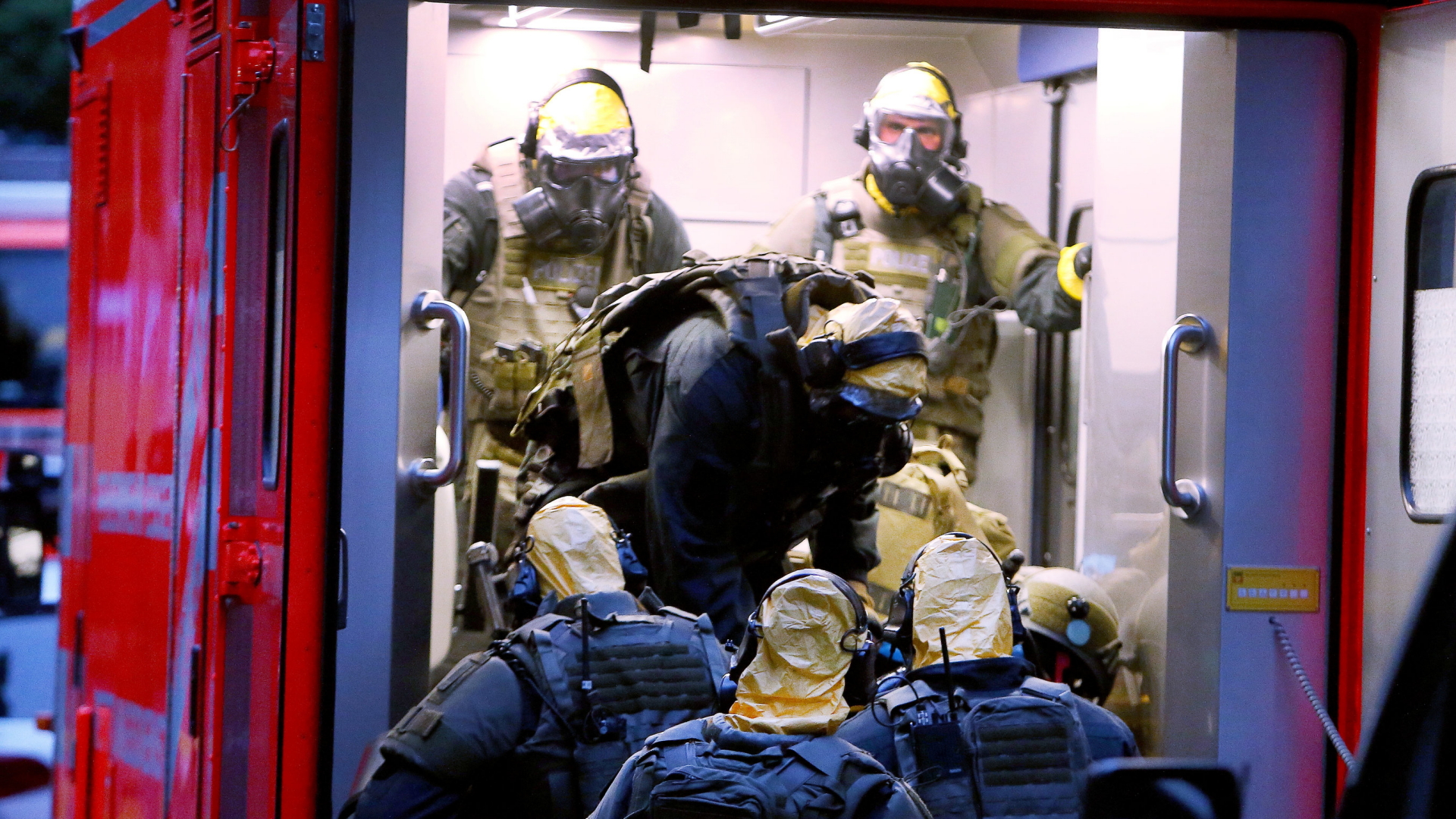 SEK Beamte mit Atemschutzmasken und Schutzanzügen steigen in einen Krankenwagen. | Bildquelle: dpa