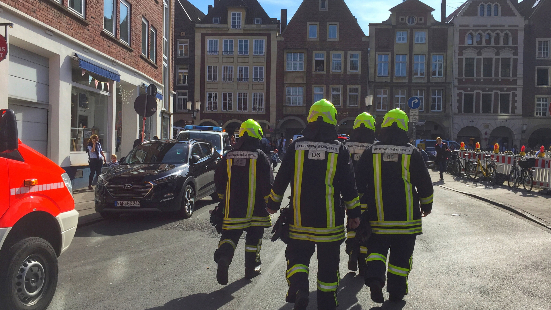 Feuerwehrmänner gehen auf einen Platz in der Altstadt von Münster zu. | Bildquelle: dpa