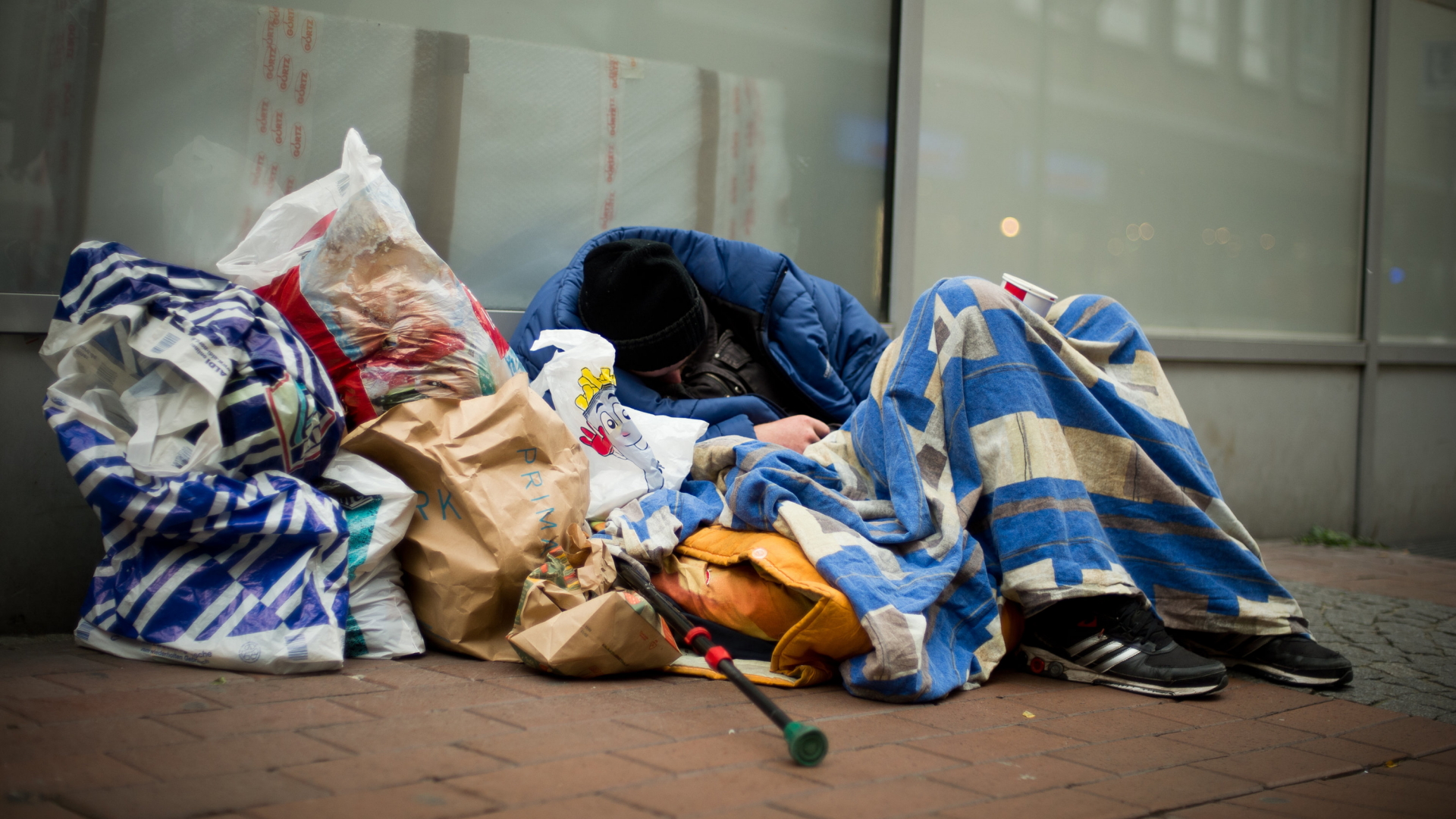 Ein Obdachloser schläft neben Tüten auf einem Bürgersteig. | Bildquelle: dpa