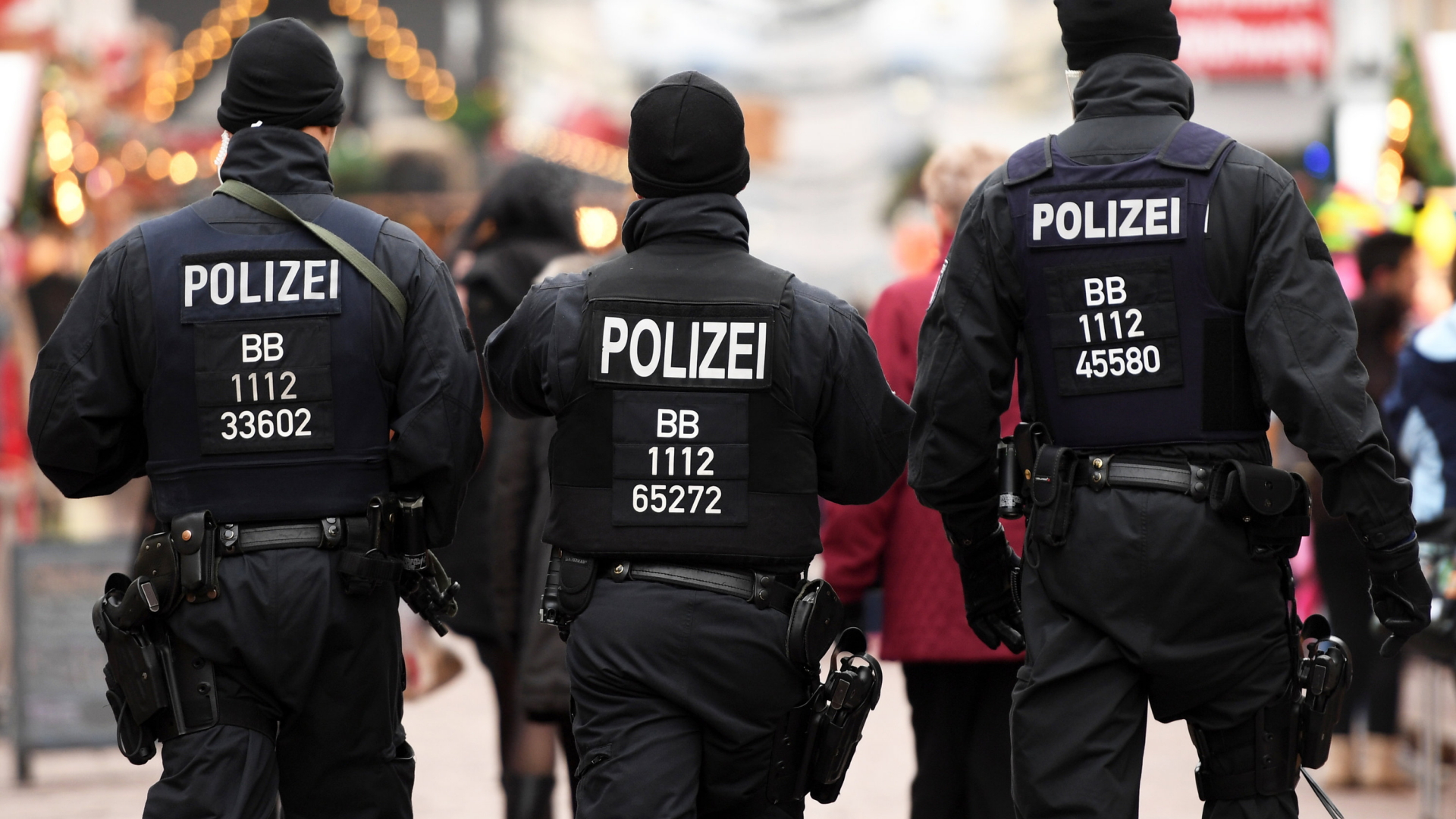 Bewaffnete Polizisten gehen in Potsdam über den Weihnachtsmarkt in der Brandenburger Straße. | Bildquelle: dpa