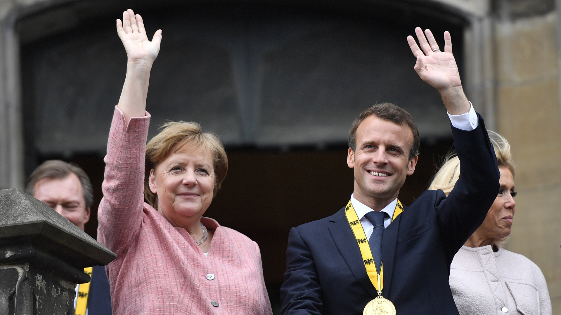 Bundeskanzlerin Angela Merkel (CDU), und der französische Staatspräsident Emmanuel Macron winken nach der Verleihung des Karlspreises an Macron von dem Balkon des Rathauses.  | Bildquelle: dpa
