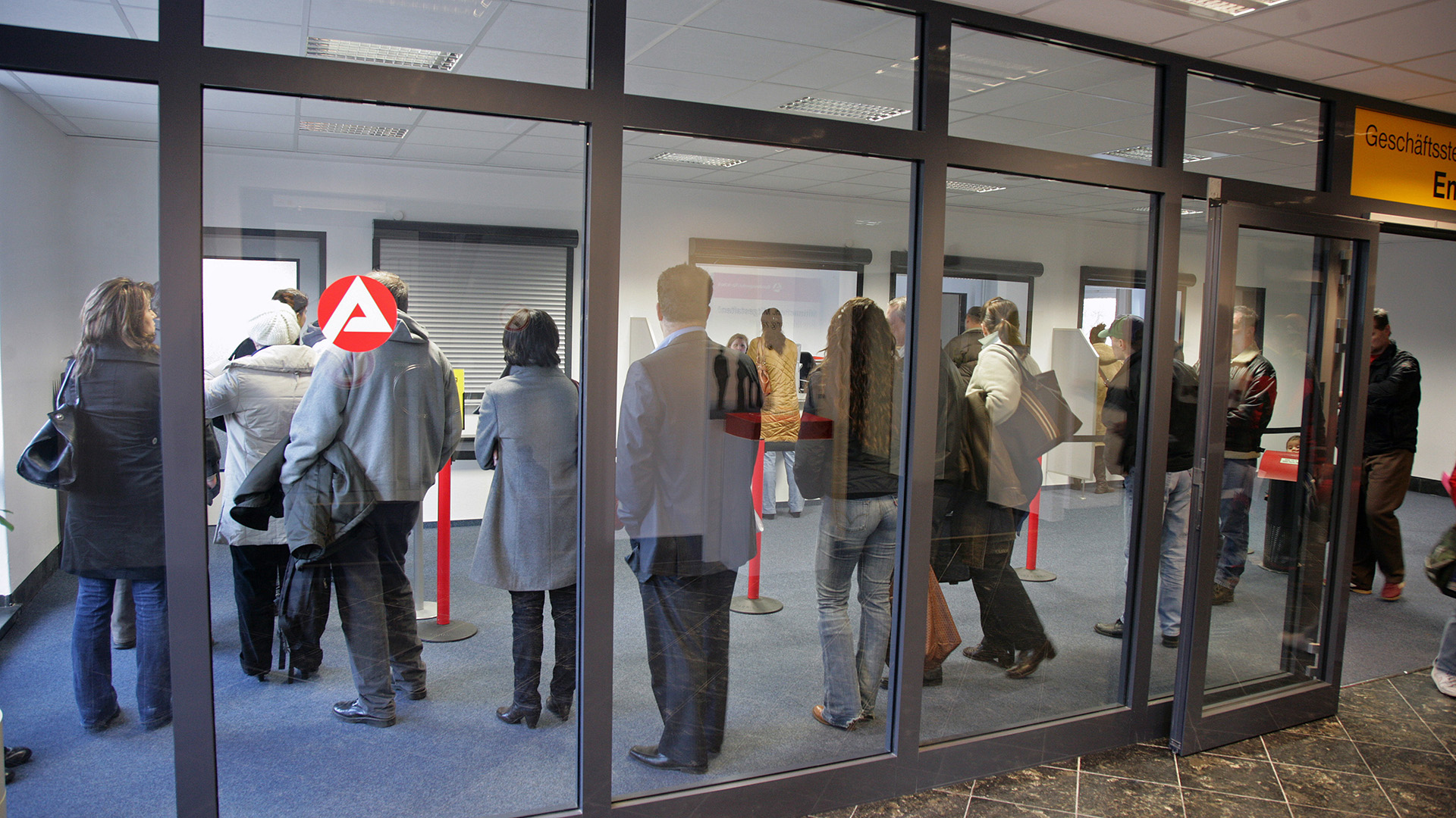 Menschen stehen in einer Agentur für Arbeit in einer Schlange. | ARD-aktuell / Dölling