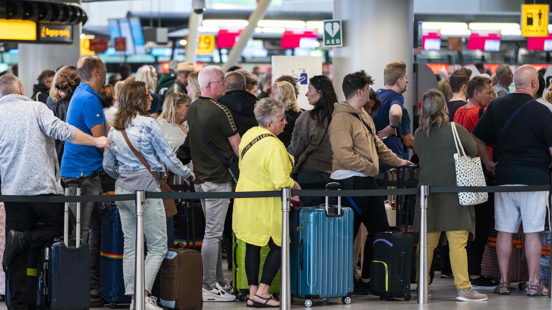 Passagiere warten vor Schaltern im Flughafen Schiphol bei Amsterdam