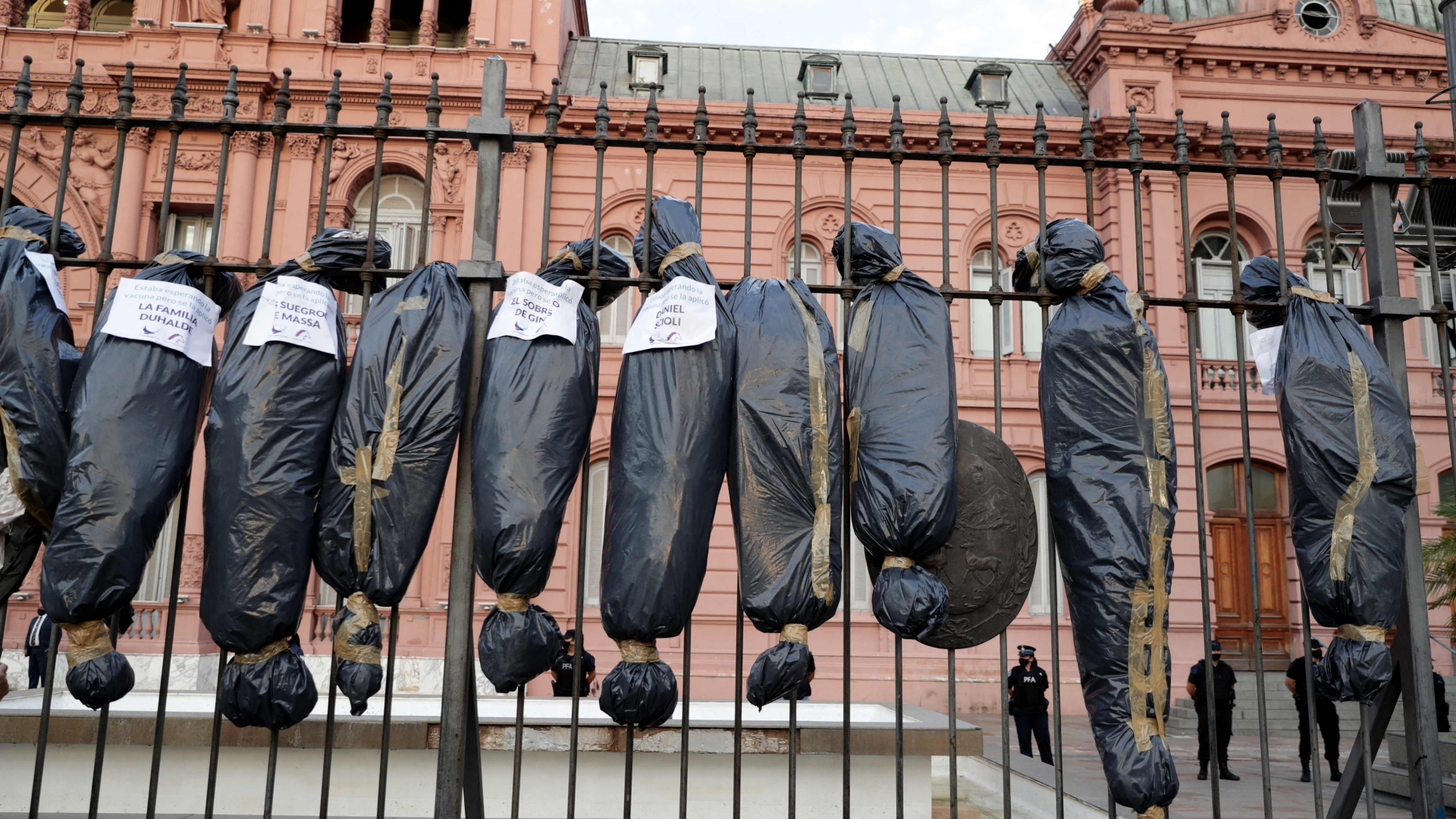 Am Zaun des argentinischen Regierungssitzes Casa Rosada in Buenos Aires befestigten Demonstranten Attrappen von Leichensäcke mit den Namen der Geimpften aus dem Umfeld der Regierung. | AFP