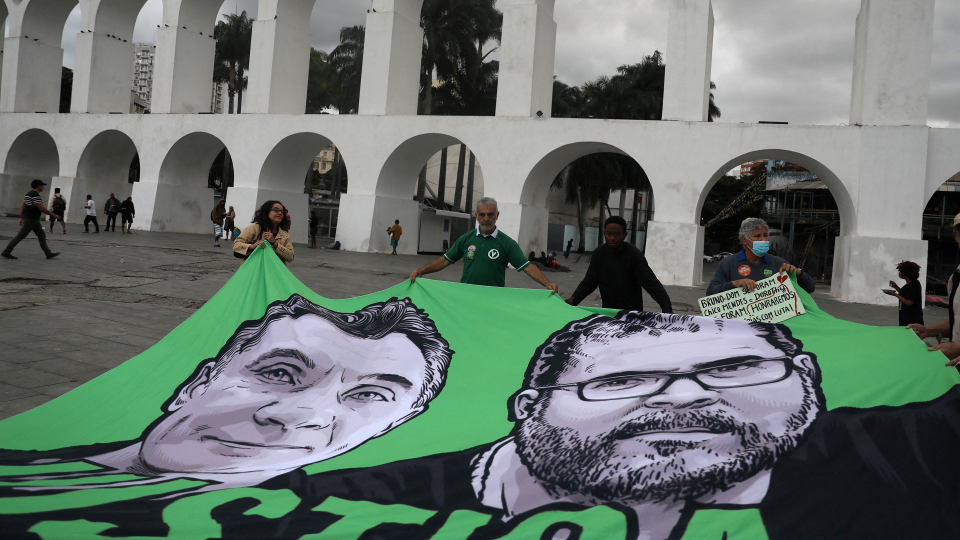 Protestierende halten ein Plakat mit den Gesichertern von Dom Phillips und Bruno Pereira in Brasilien hoch. | Bild: REUTERS/Pilar Olivares/File Photo