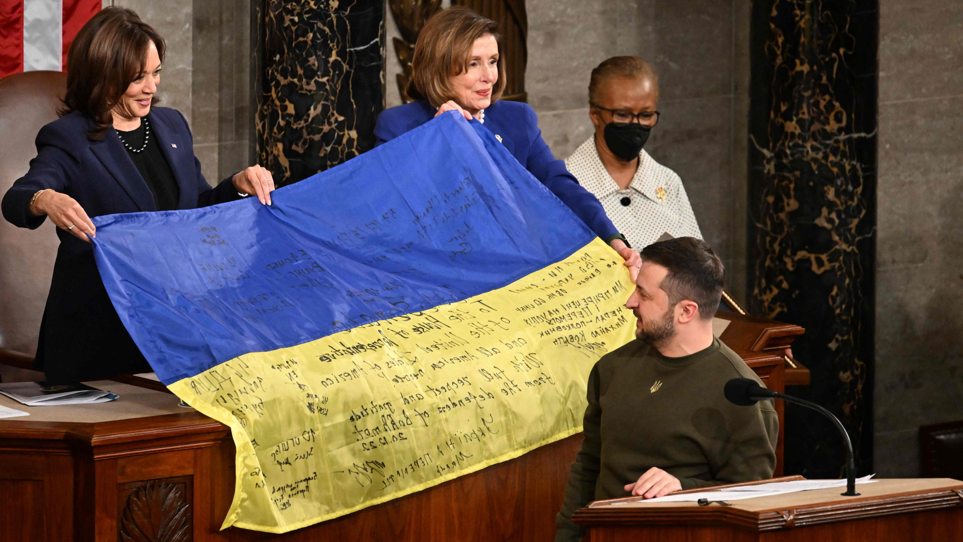 Die Vorsitzende des US-Repräsentantenhauses, Nancy Pelosi, hält gemeinsam mit US-Vizepräsidentin Kamala Harris eine ukrainische Flagge während einer Rede des ukrainischen Präsidenten Wolodymyr Selenskyj hoch. | AFP
