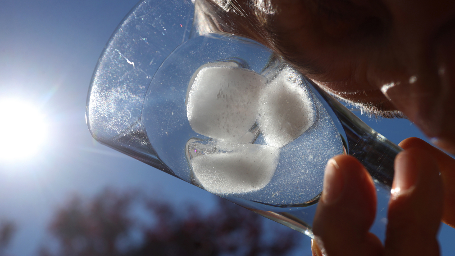 Eine Person hält sich ein Glas mit Eiswürfeln an die Schläfe. | dpa
