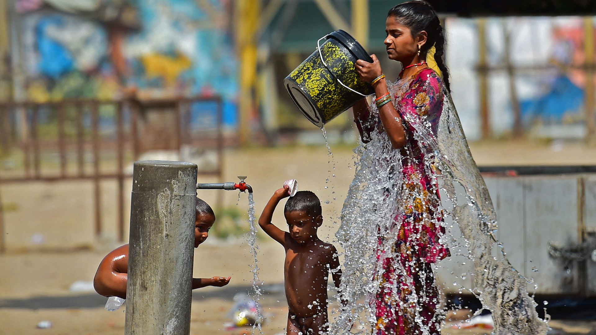 Eine Inderin erfrischt sich mit einem Eimer Wasser. | AFP