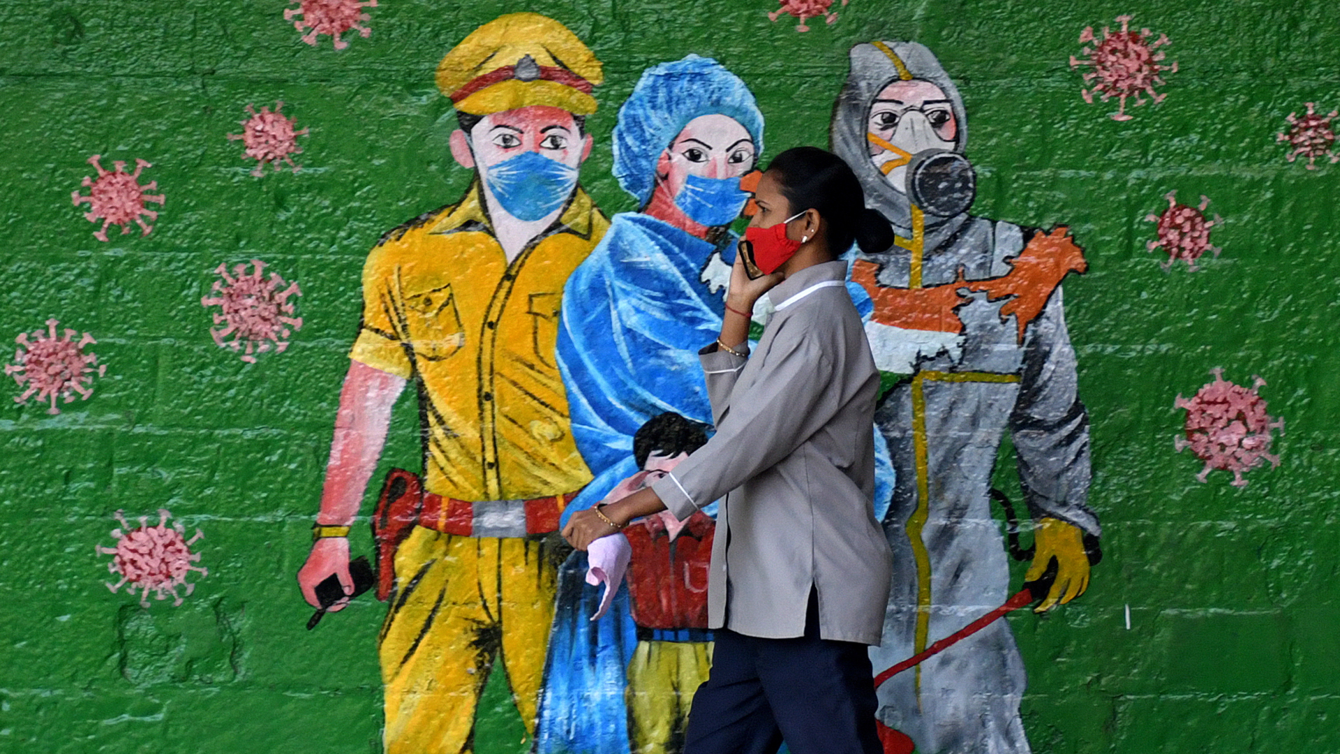 Eine Frau geht in Mumbai an einem Graffiti vorbei, das auf das Tragen von Mund-Nasen-Masken aufmerksam macht. 