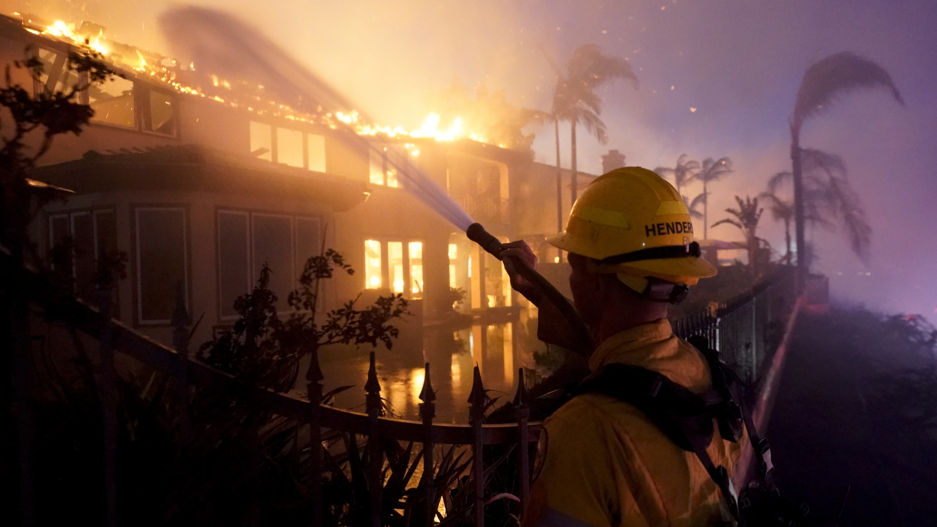 Ein Feuerwehrmann versucht, ein brennendes Gebäude während eines Waldbrandes zu löschen. | dpa/AP
