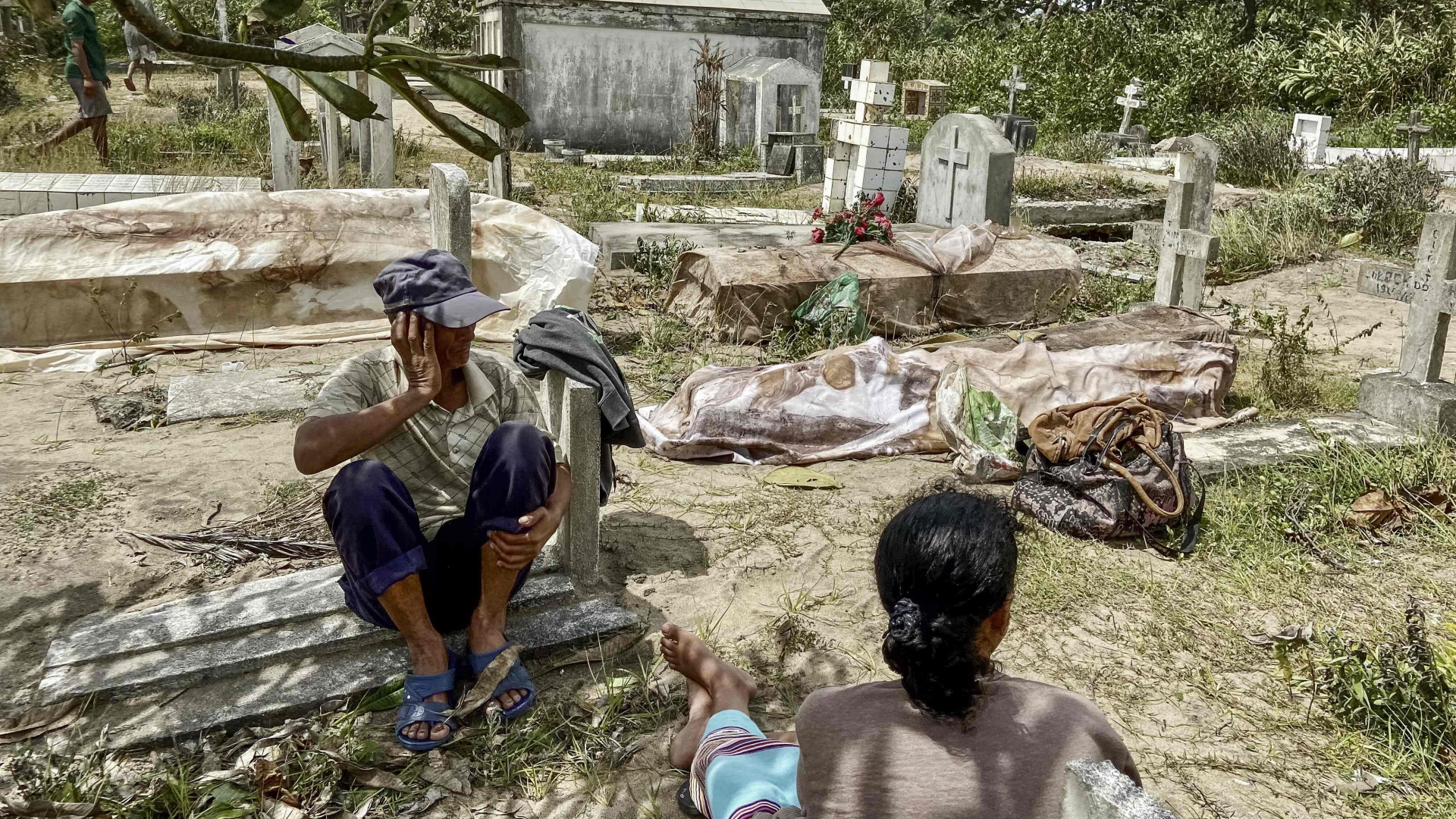 Angehörige sitzen auf einem Friedhof in Mahanoro neben den Leichen, die aus den vom Zyklon zerstörten Gräbern exhumiert wurden. | AFP