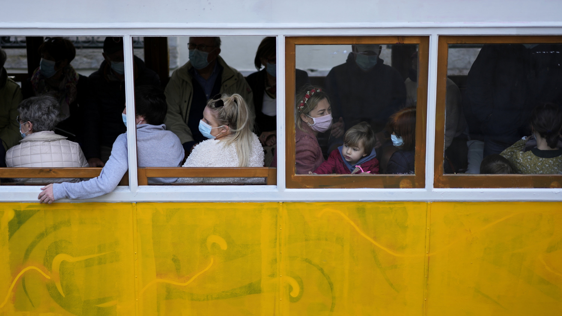 Menschen sitzen in Lissabon mit Maske in einer Bahn. | AP