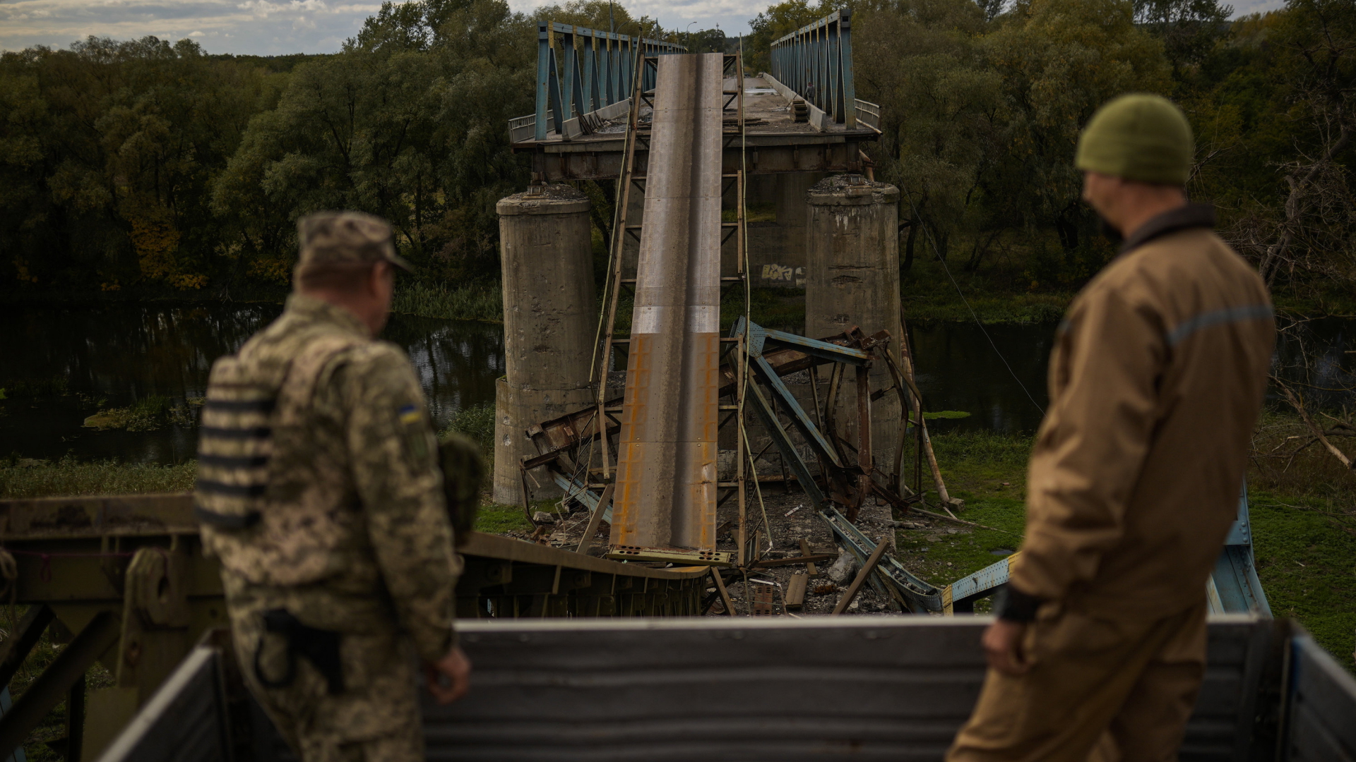 Ukrainische Soldaten entfernen am Montag, 3. Oktober 2022, bei der Arbeit an einer Brücke in Izium, Teile einer Metallstruktur, die während der Kämpfe mit russischen Truppen beschädigt wurde.