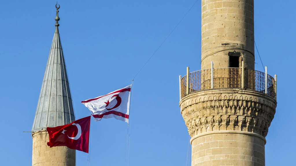 Die Flaggen des türkischen und des griechischen Teil Zyperns wehen zwischen zwei Minaretttürmen. | dpa