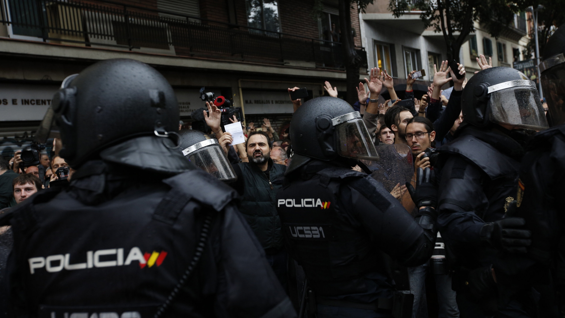 Polizeikette und Wähler mit Stimmzettel in Barcelona | AP