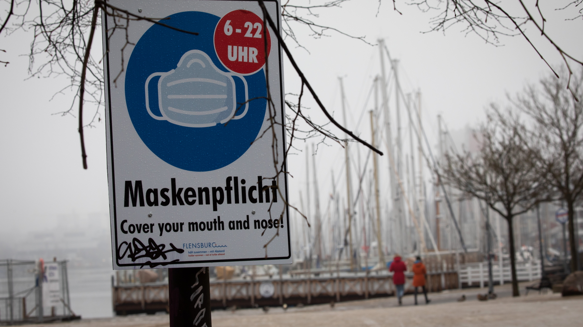Ein Hinweisschild zur Maskenpflicht ist an der Hafenspitze in der Flensburger Innenstadt zu sehen.