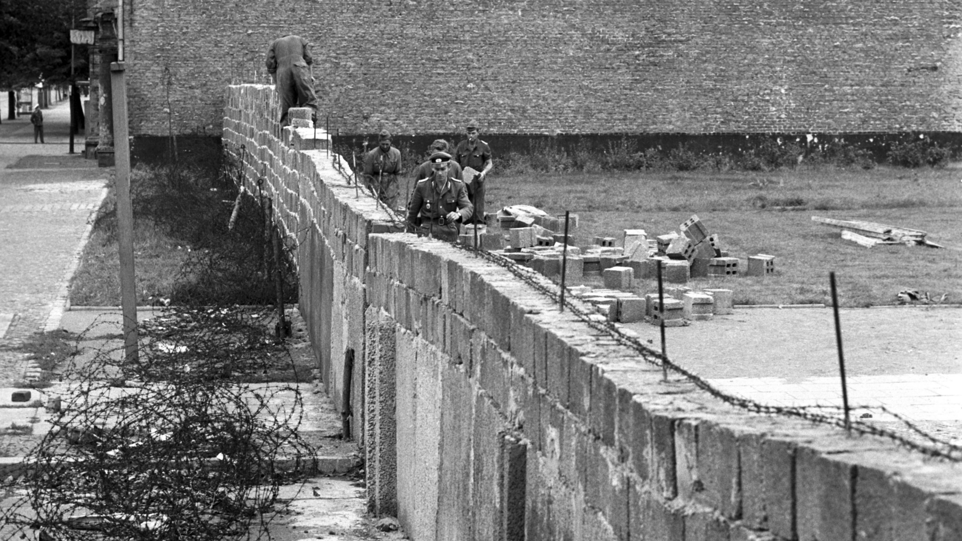 Volkspolizisten und Arbeiter der DDR beim Bau der Mauer im Norden Berlins. | dpa