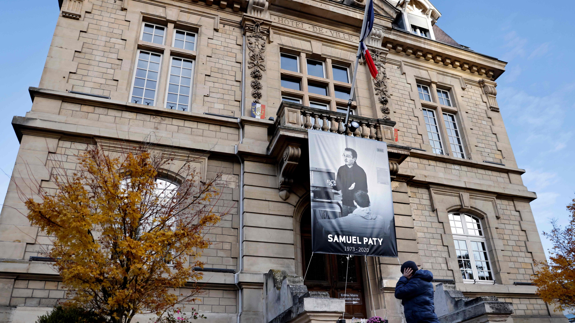 Ein Fußgänger geht an einem Plakat vorbei, das den Französischlehrer Samuel Paty zeigt - am Rathaus in Conflans-Sainte-Honorine 