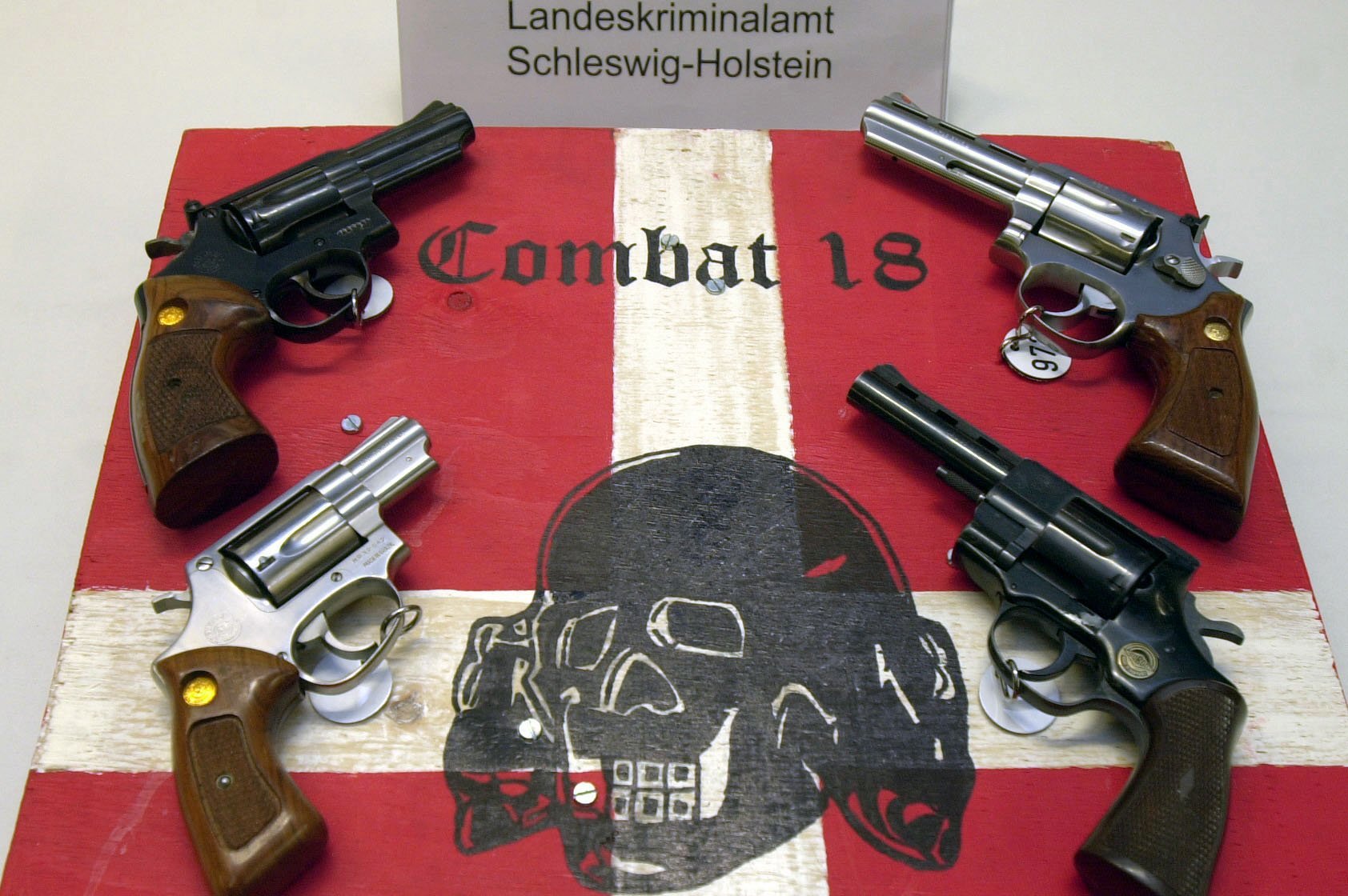 Sichergestellte Waffen und ein Schild der kriminellen Neonazi-Gruppe "Combat 18" liegen im schleswig-holsteinischen Landeskriminalamt in Kiel. | picture-alliance / dpa/dpaweb