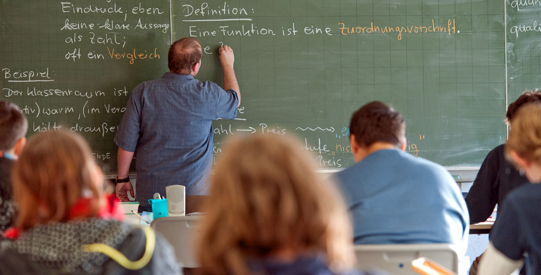 Ein Lehrer steht an der Tafel und schreibt. | picture alliance / dpa
