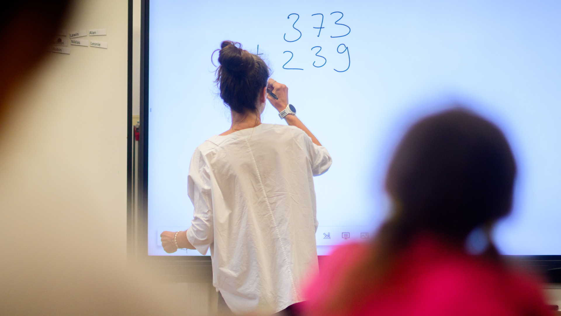 Eine Lehrerin unterrichtet Mathematik an einem Whiteboard.