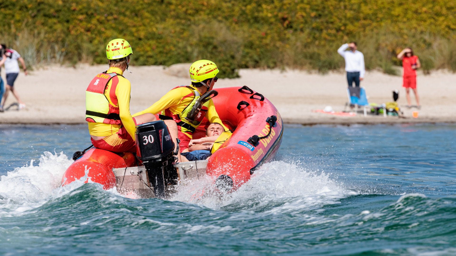 DLRG-Rettungsschwimmer bringen bei einer Übung einen Statisten zurück an den Strand. | dpa