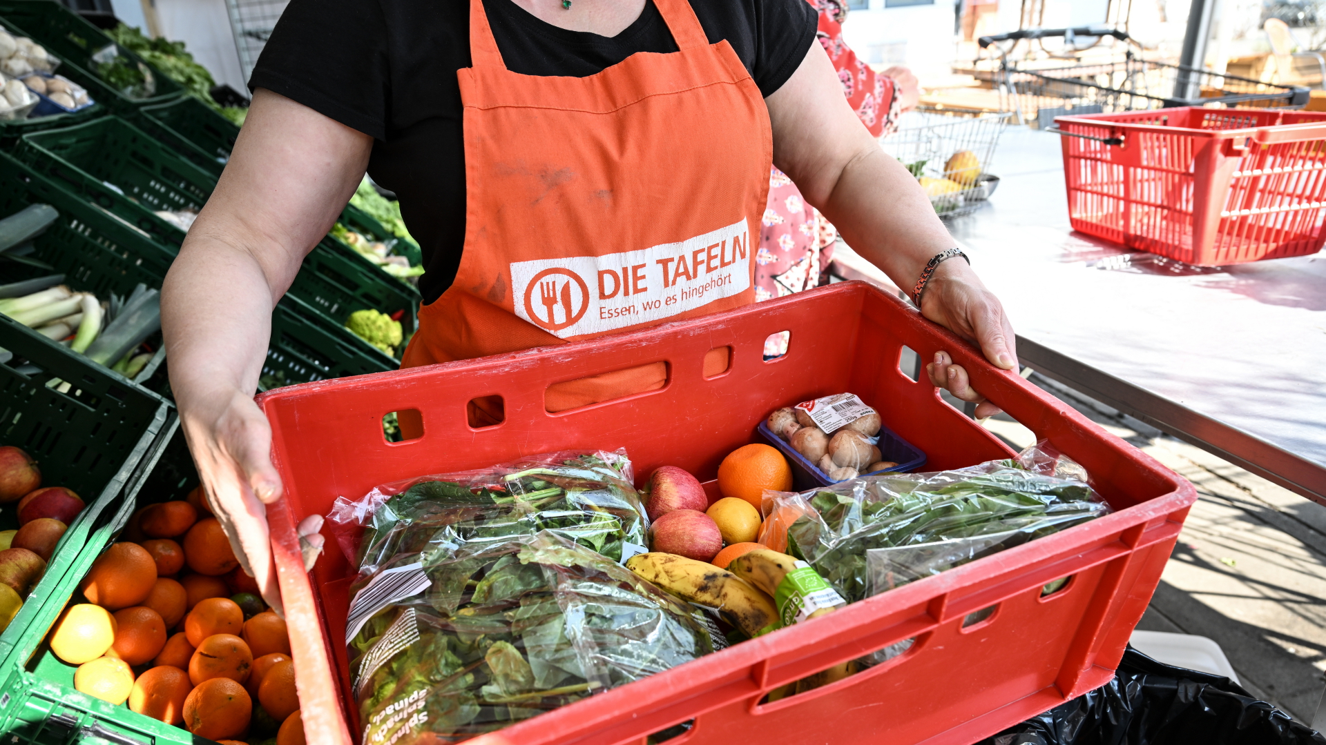 Eine Mitarbeiterin bei den Tafeln trägt eine Kiste mit Obst und Gemüse | dpa