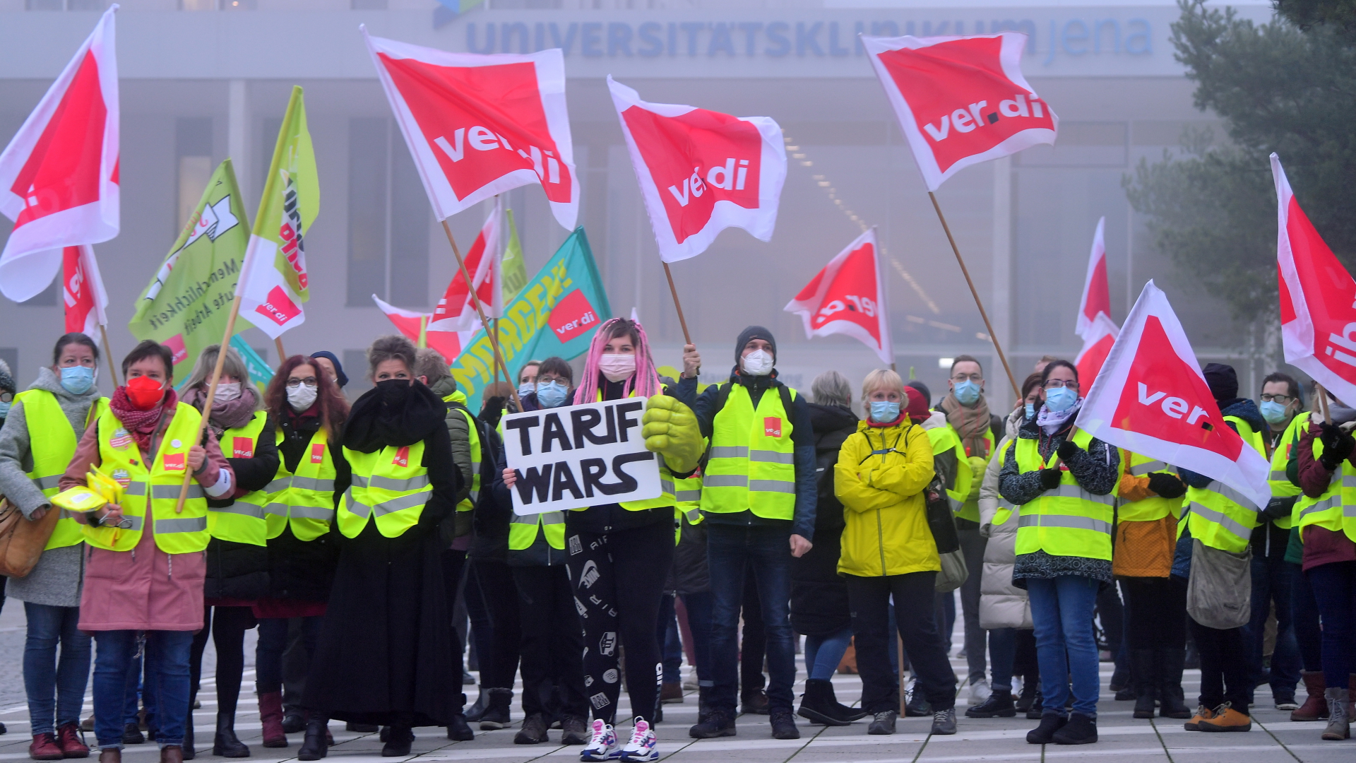 Streikende vor dem Universitätsklinikum Jena mit dem Schriftzug "Tarif Wars" auf einem Plakat. | dpa