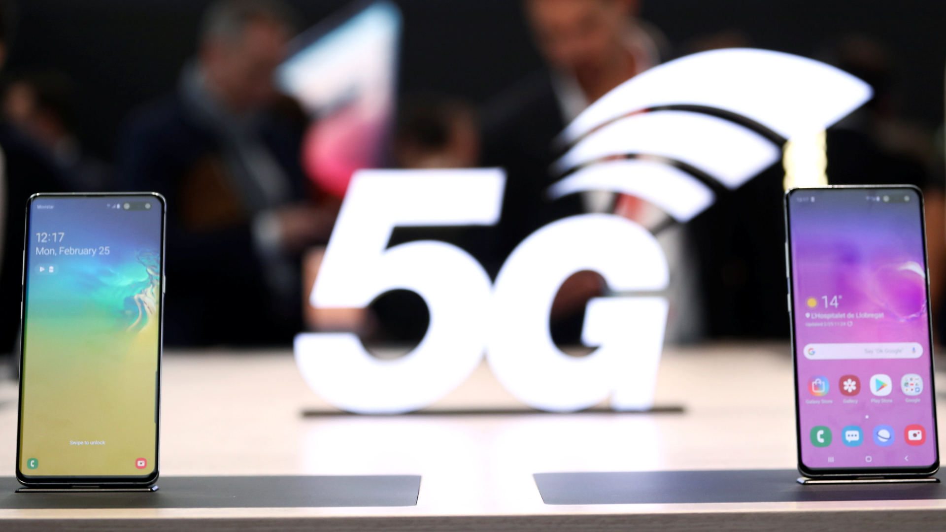 Zwei Handys sind auf einem Tisch aufgestellt, im Hintergrund ist der Schriftzug "5G" zu sehen.