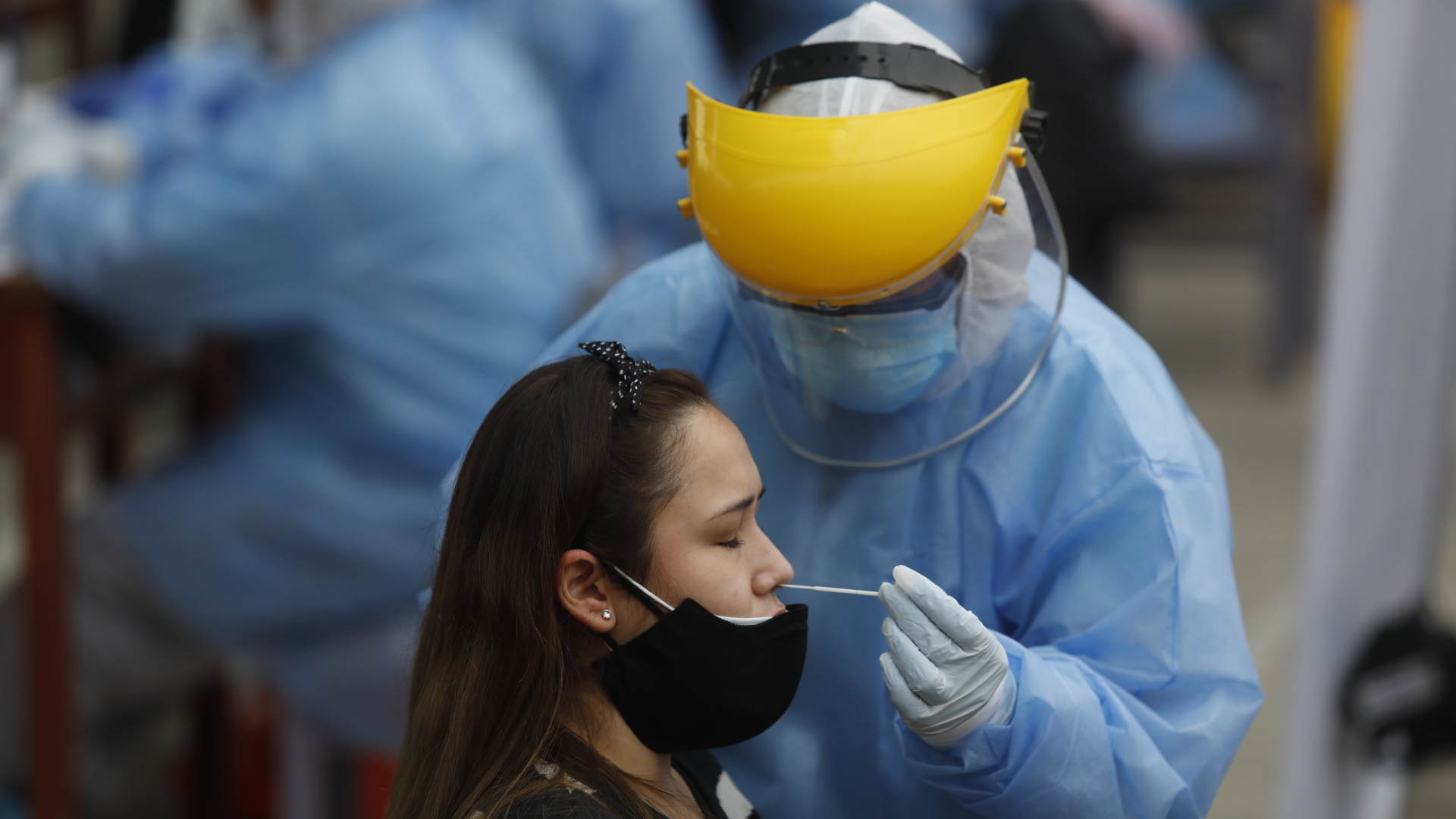 Ein medizinischer Mitarbeiter in Schutzkleidung nimmt einen Nasenabstrich bei einer Patientin, um sie auf das Coronavirus zu testen.