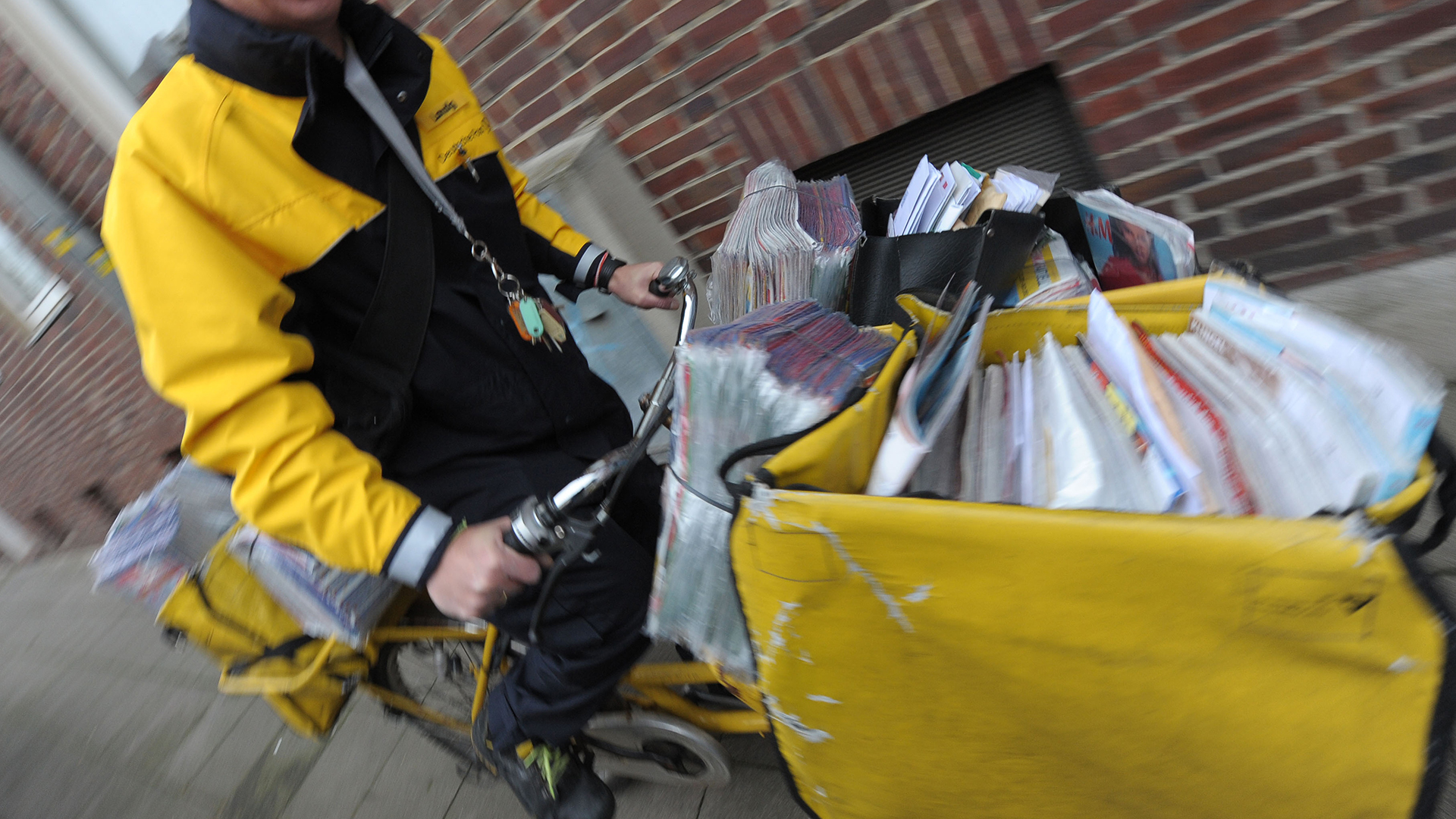 Ein Postbote fährt mit seinem Fahrrad die Post aus. | picture alliance / dpa