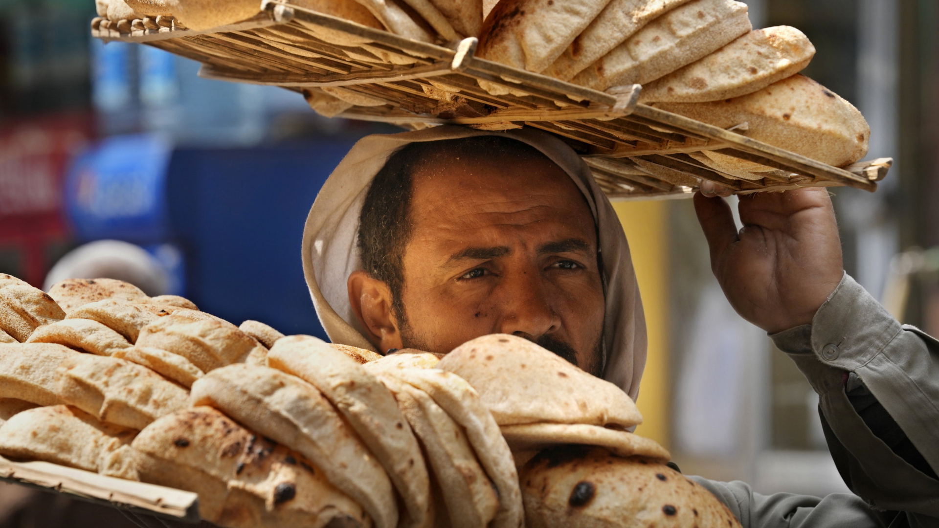 Ein Mann in einer Bäckerei in Kairo (Ägypten) trägt mehrere Bleche mit Brot | AP