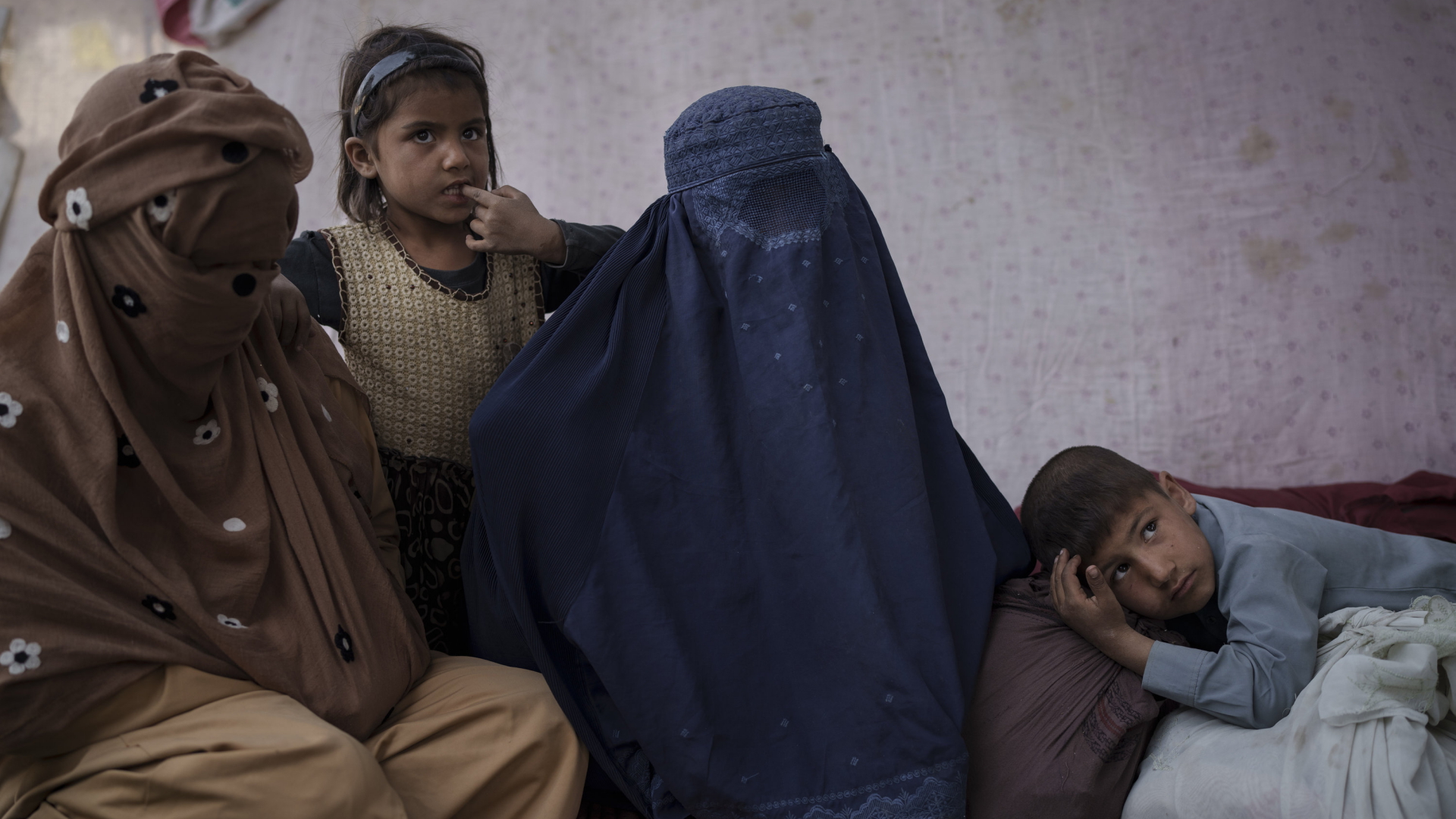 Eine Frau sitzt mit ihren Kindern an einer Bushaltestelle in Afghanistan  | AP