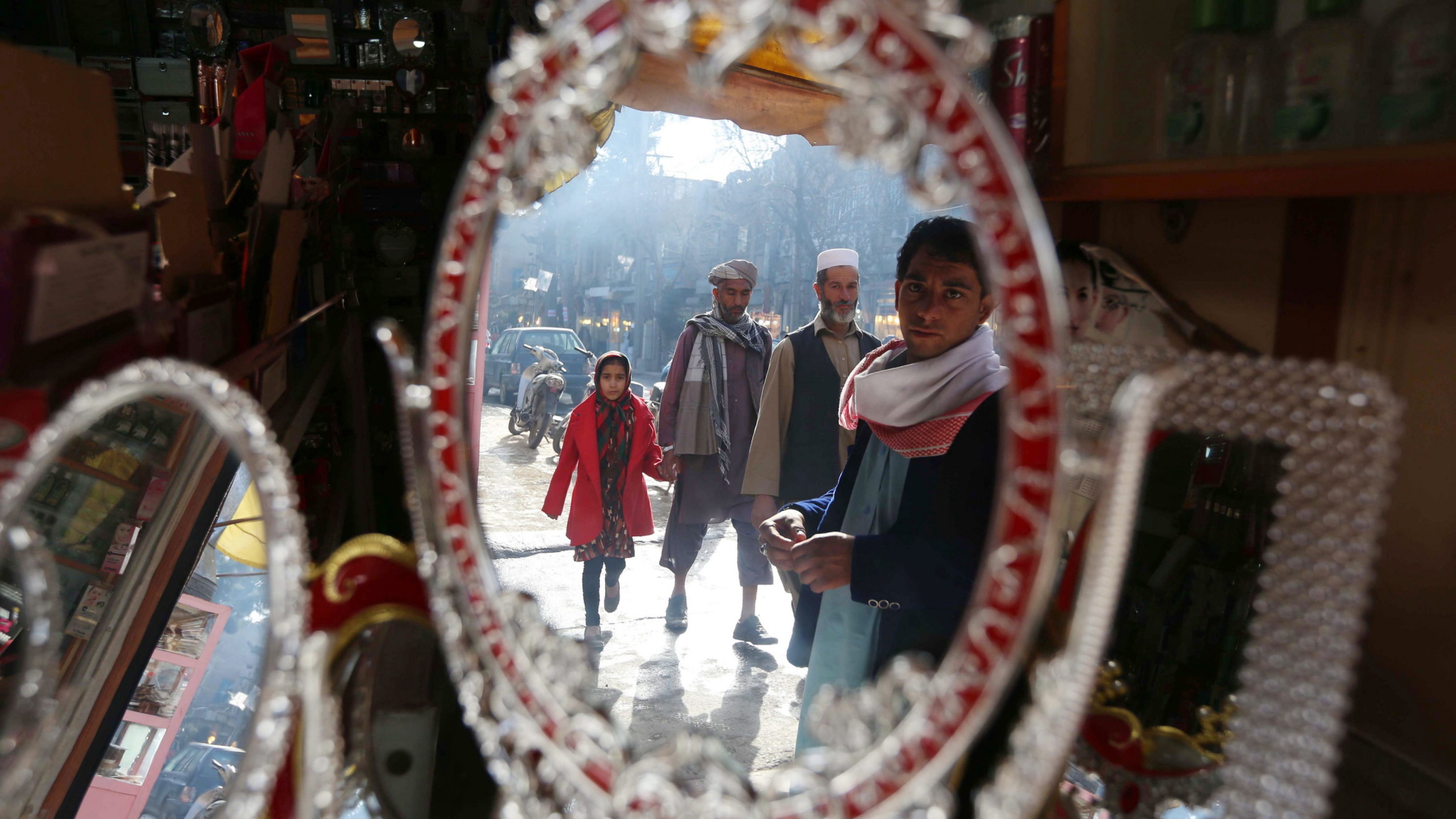 Menschen spiegeln sich in einem Spiegel auf einem Markt in Afghanistan.
