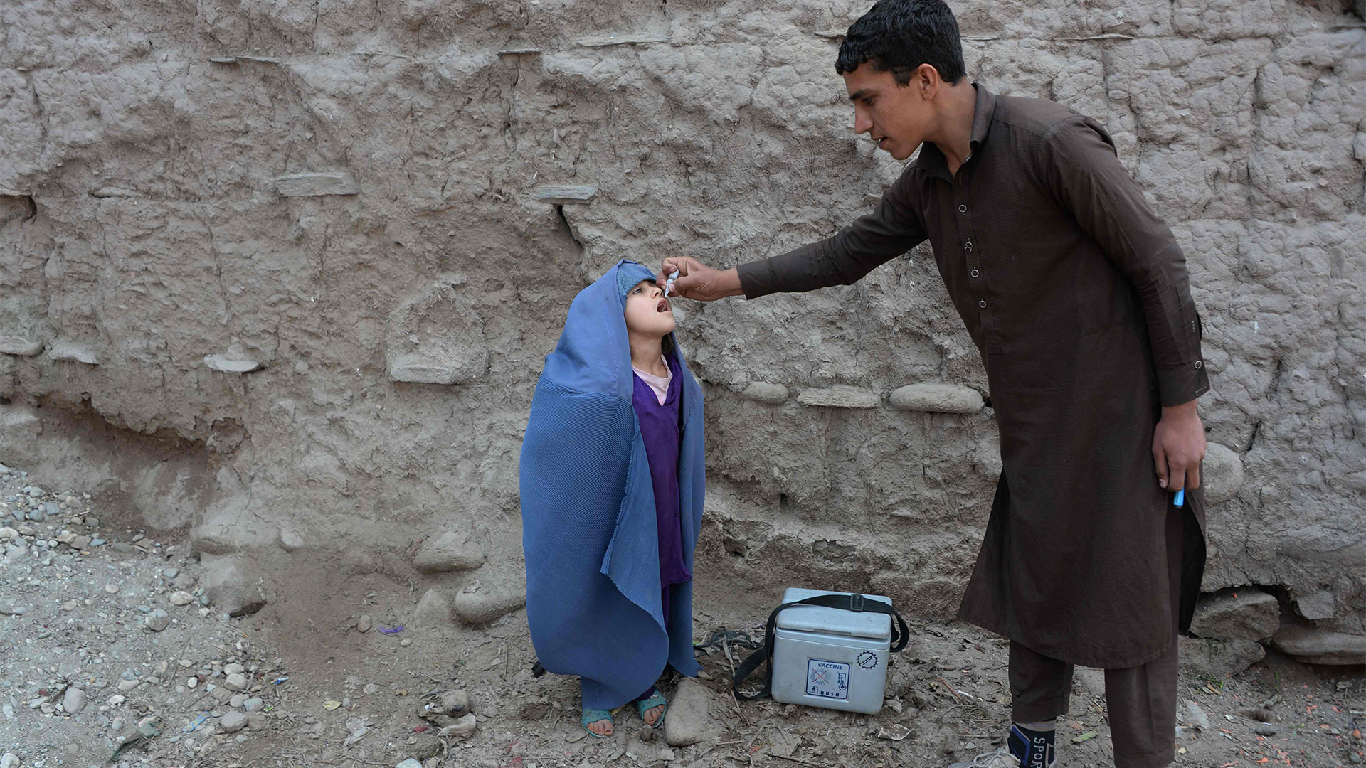 Ein afghanischer Helfer verabreicht den Polio-Impfstoff an ein Kind während einer Impfkampagne am Stadtrand von Jalalabad | AFP