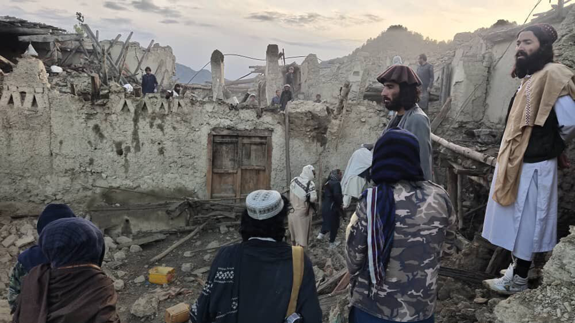 Mehrere Menschen betrachten die Zerstörung durch ein Erdbeben in der Provinz Paktika im Osten Afghanistans. | AP