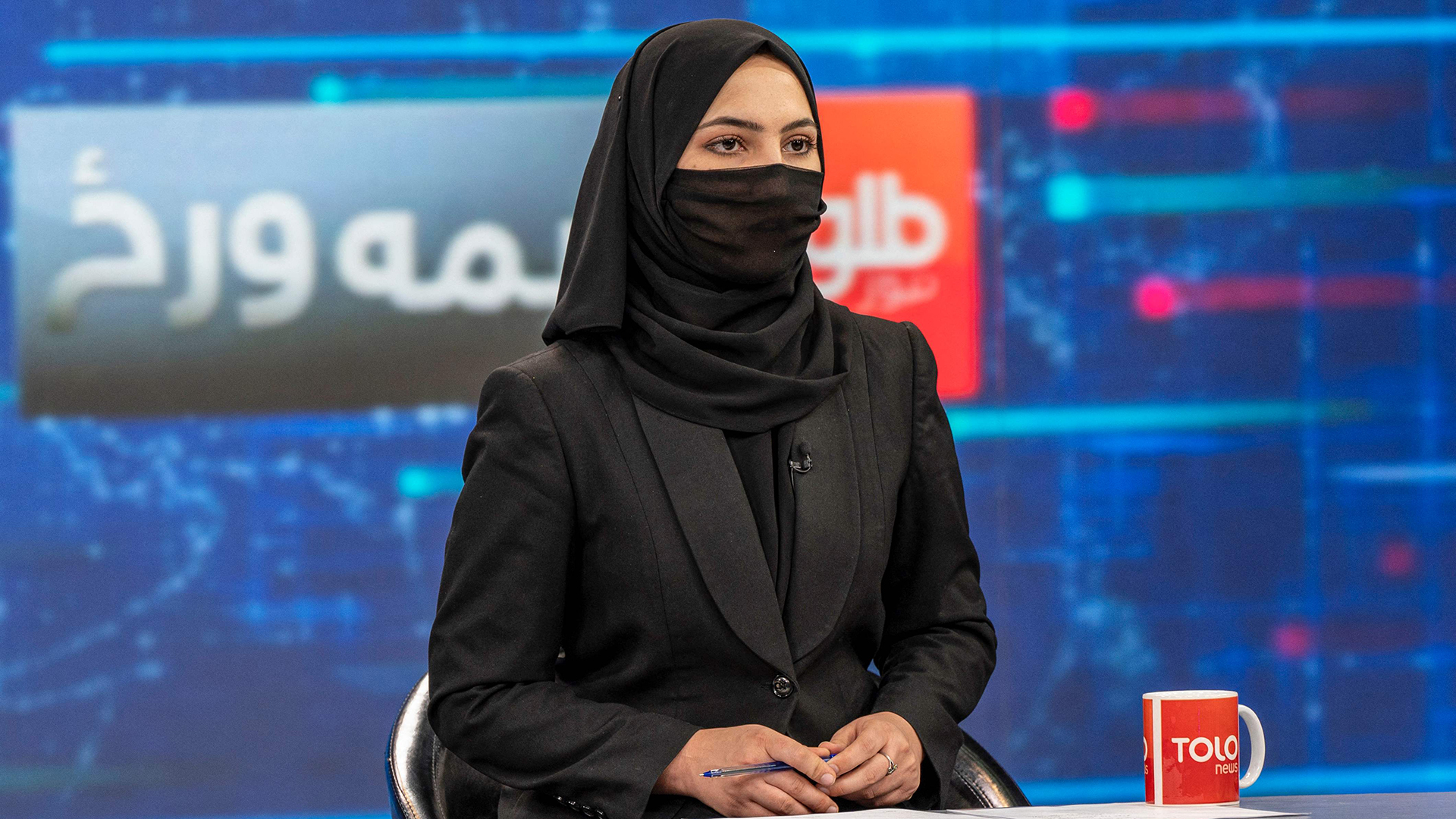 Eine Moderatorin trägt bei den TV-Aufnahmen Kopftuch und hat Mund und Nase bedeckt. | AFP