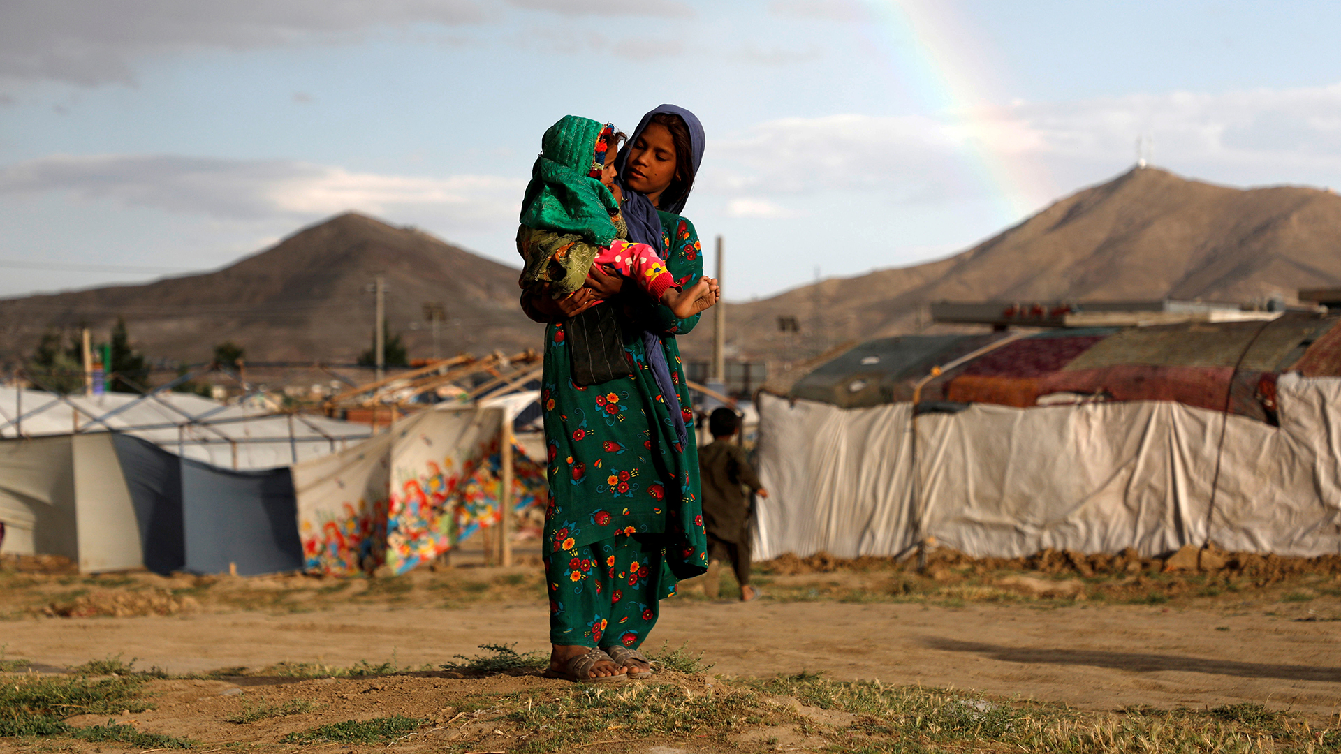 Ein afghanisches Mädchen trägt in einem Flüchtlingscamp nahe Kabul ein Kleinkind auf dem Arm.