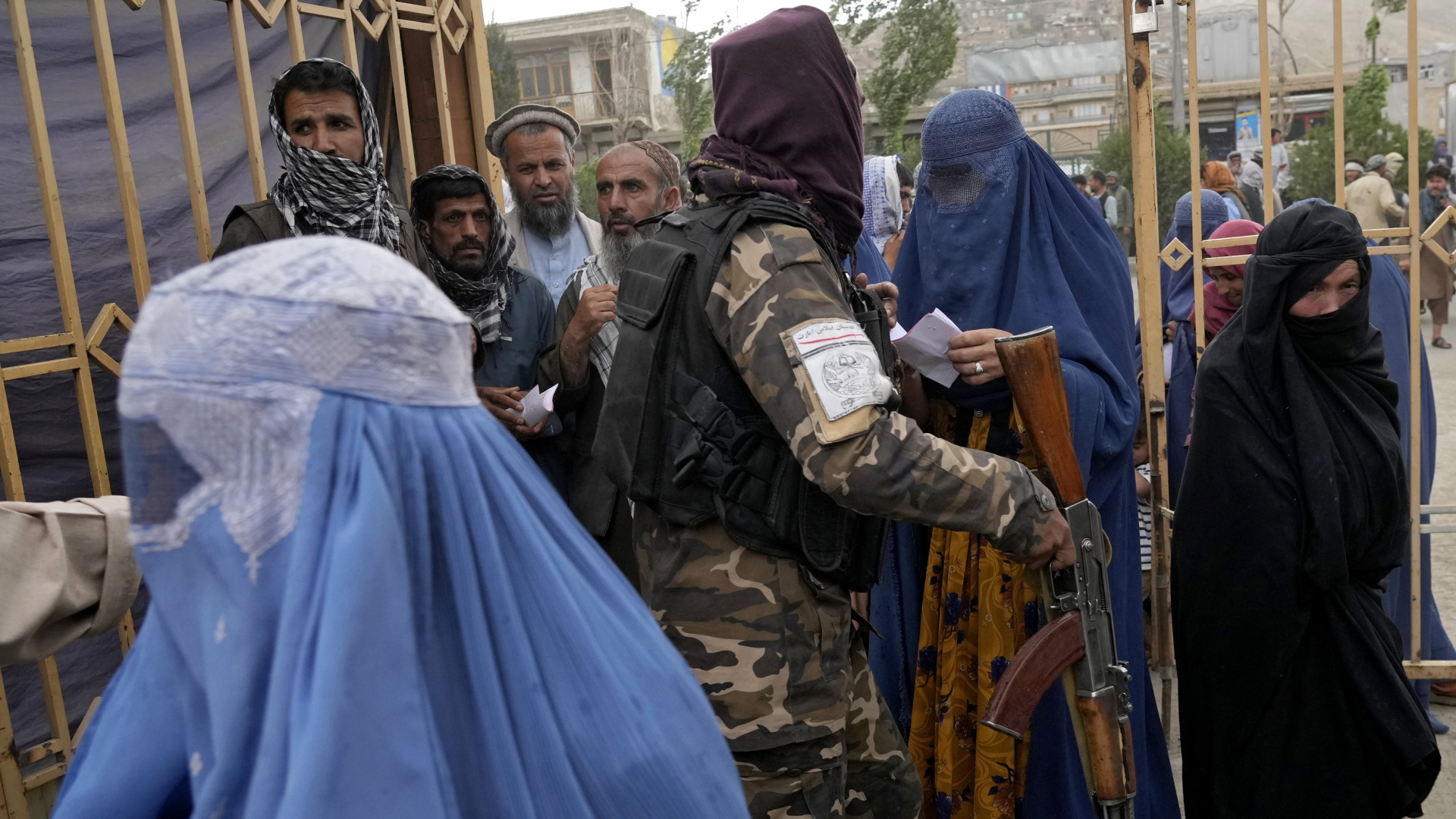 Ein Taliban steht zwischen mehreren Frauen und Männern, die sich Essensrationen abholen. | AP