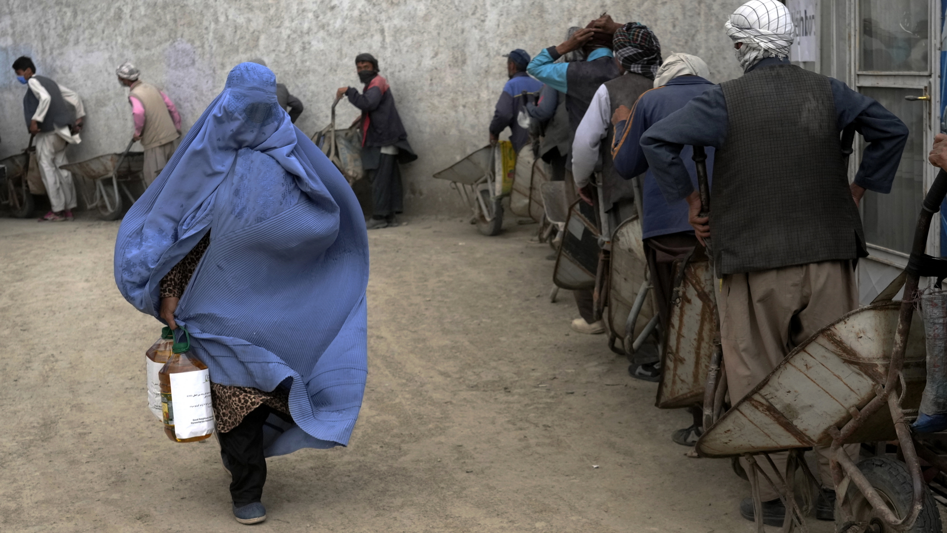 Eine verschleierte Frau in Kabul geht mit eine Lebensmittelration davon, die sie von einer Hilfsorganisation erhalten hat. 