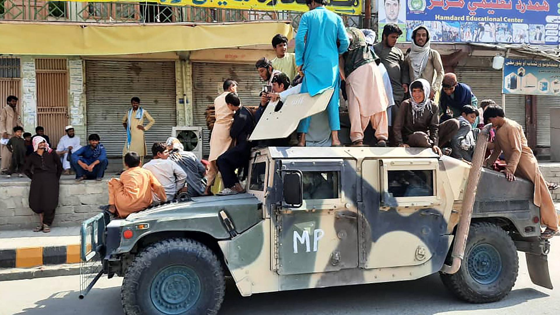 Taliban-Kämpfer und Zivilisten stehen oder sitzen auf einem von der afghanischen Armee erbeuteten Hummer aus US-Produktion (Provinz Laghman, 15. August 2021). | AFP
