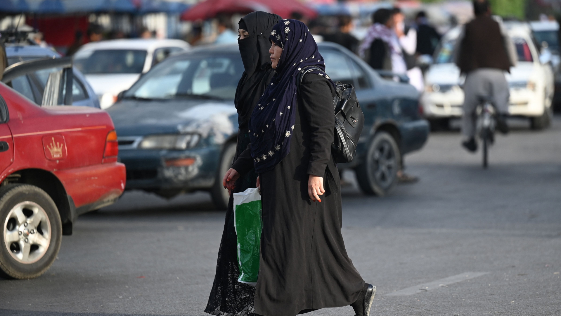 Zwei Frauen mit Kopftuch und Burka laufen über eine Straße im afghanischen Kabul. | AFP