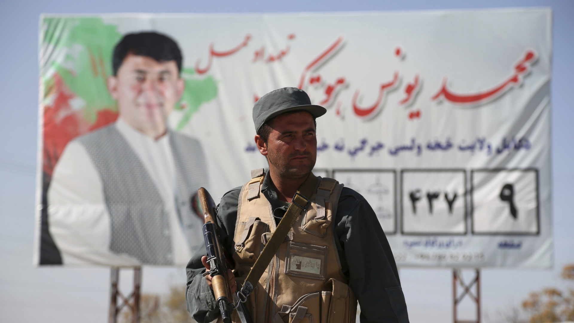 Ein bewaffneter afghanischer Polizist steht an einem Kontrollpunkt auf dem Gelände der unabhängigen Wahlkommission vor einem Wahlplakat.  | Bildquelle: dpa